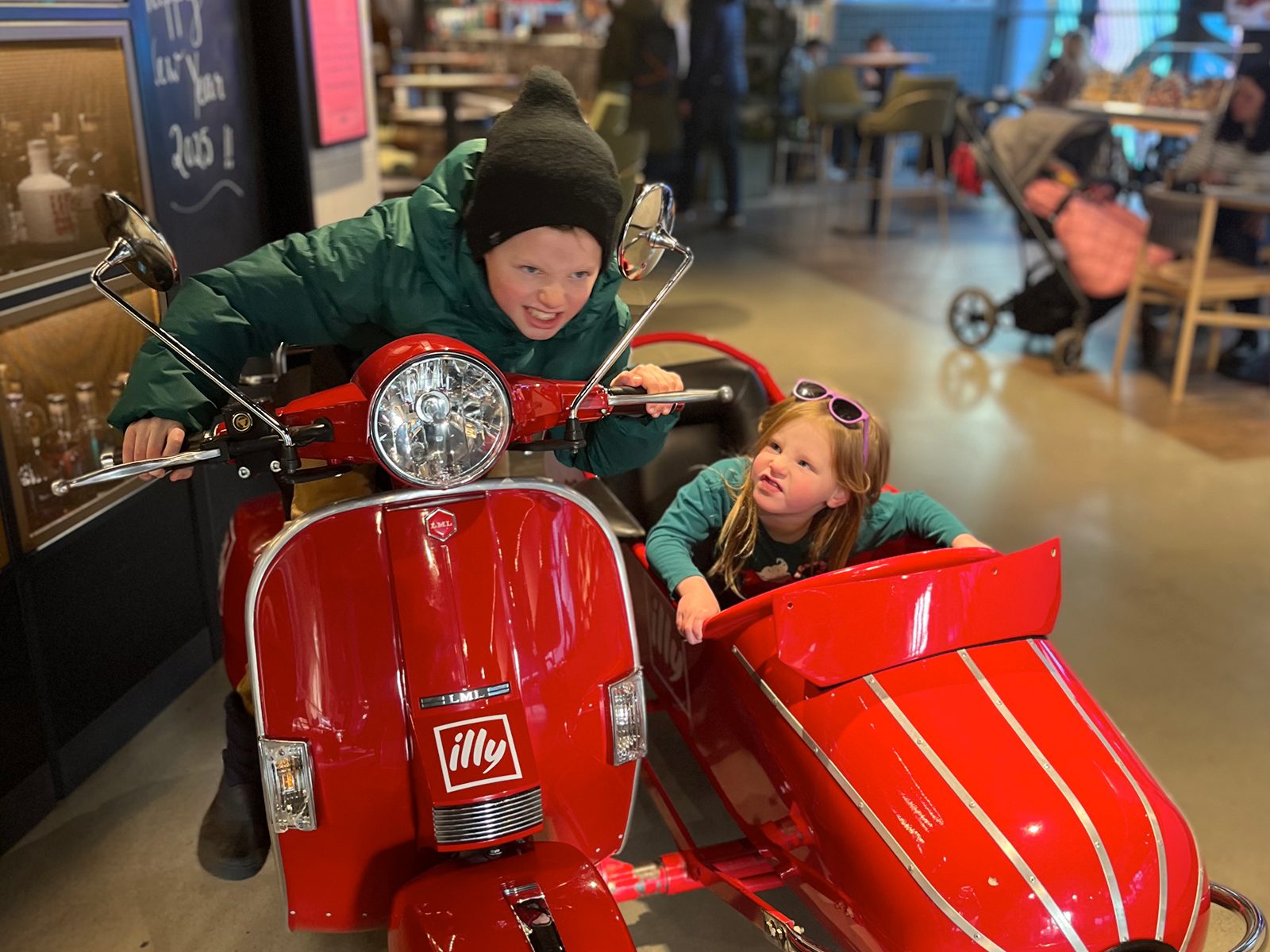 Calvin and Amelia on a red Vespa with sidecar in an Edinburgh café