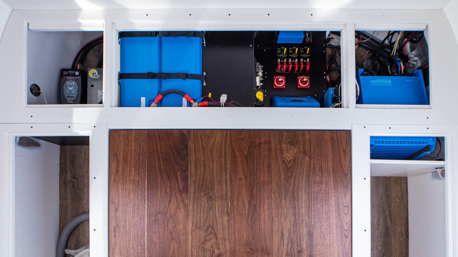 The installed Victron electrical system inside Colletta, showing the blue inverter, charge controllers, and battery monitor