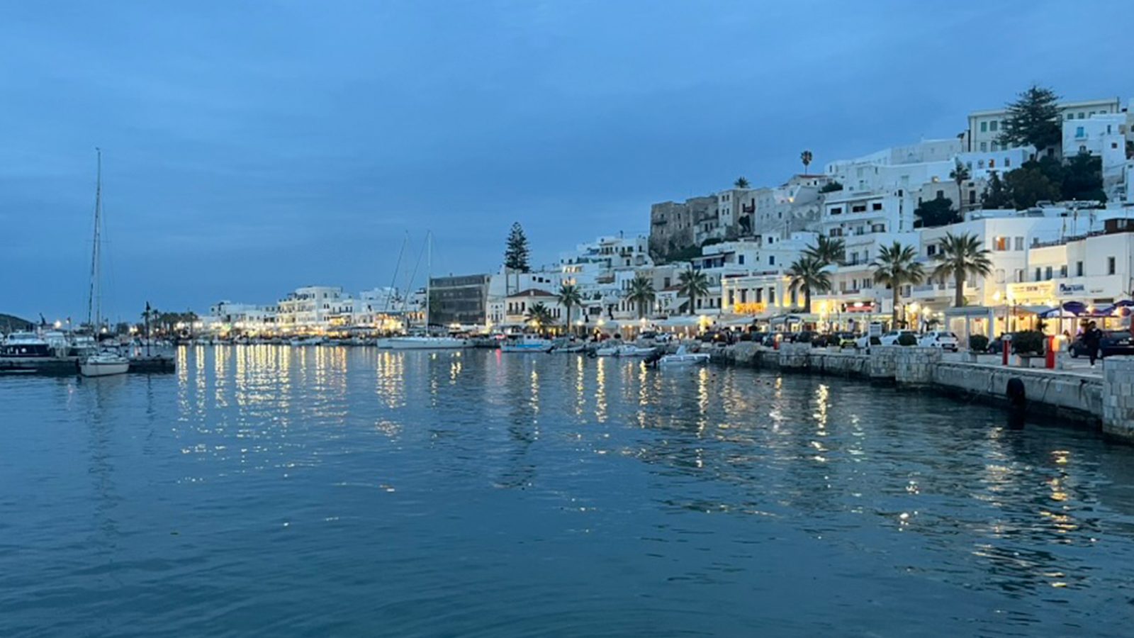 Naxos harbor at dusk, white buildings reflecting in calm water