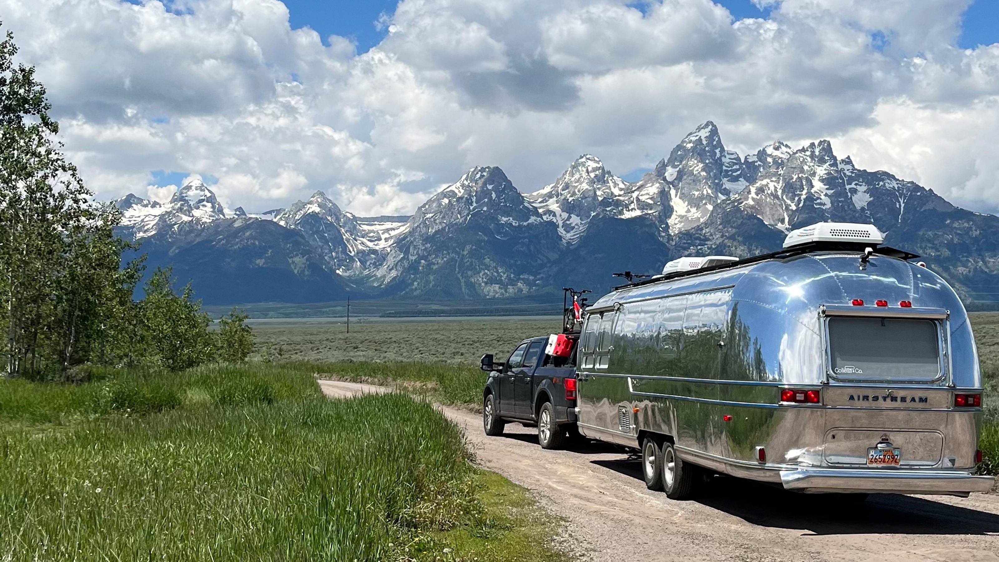 Colletta and Frank on a dirt road with the Grand Tetons rising behind them